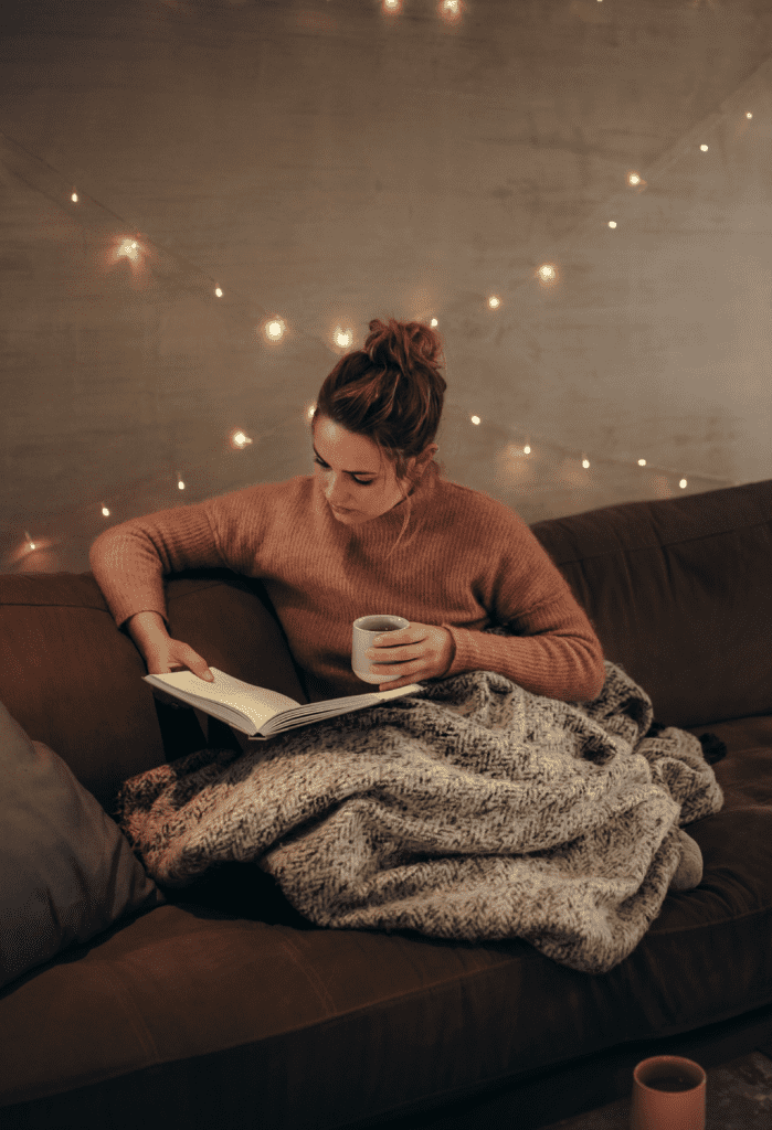 Women on her couch reading a book in the evening